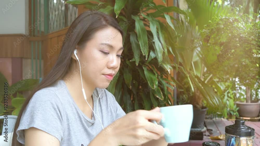 A woman is sitting at a table with a laptop and a cup of coffee. She is wearing a grey shirt with the word A woman is sitting at a table with a laptop and a cup of coffee. She is wearing a grey shirt with the word