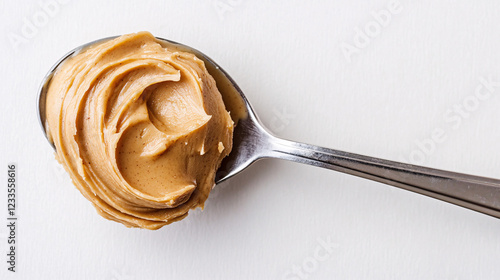close up of a teaspoon full of creamy peanut butter on a white background