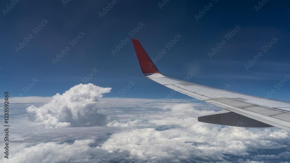 The wing of an airplane in the blue sky. Beautiful white cumulus clouds below. View from the plane window. Malaysia. The wing of an airplane in the blue sky. Beautiful white cumulus clouds below. View from the plane window. Malaysia.
