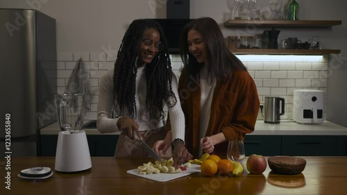 Lesbian multiracial couple in casual clothes are feeding each other and showing love in a modern kitchen at home.