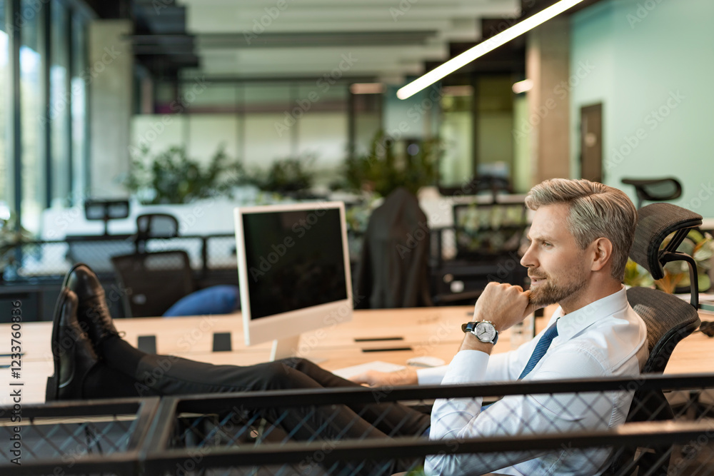 Portrait of a delighted businessman relaxing in his office. Portrait of a delighted businessman relaxing in his office.