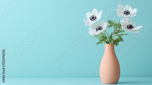 Two white anemone flowers elegantly arranged in a peach fuzz color vase against a minimal background. photo