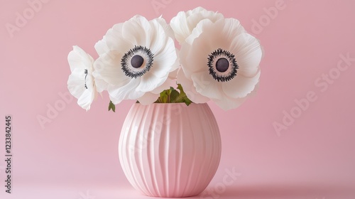 Two white anemone flowers elegantly arranged in a peach fuzz color vase against a minimal background. photo