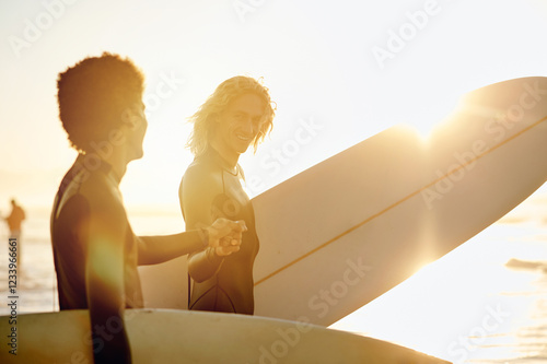 Canvas Print Fist bump, surfer and friends by the waves with sunset lens flare ready for water sport in the ocean