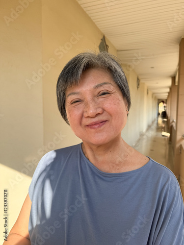 Vertical photo of Happy asian Thai Chinese elder woman smiling to camera while at home or traveling and staying hotel. photo