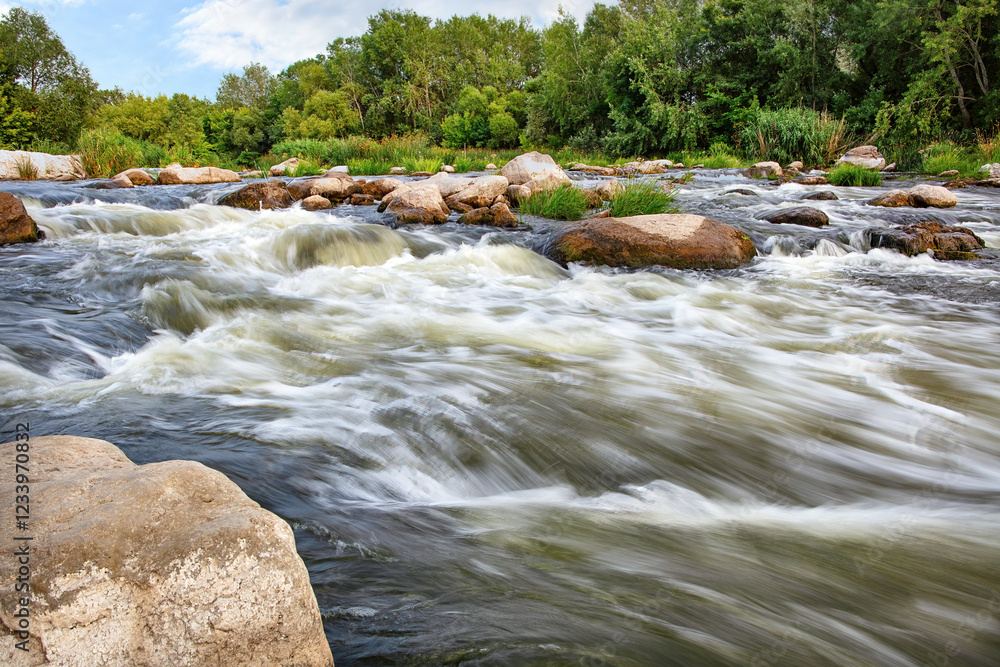 Flowing river dances over smooth stones in a serene natural landscape