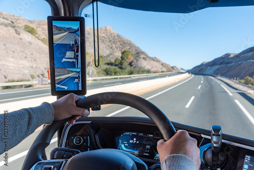 Tablou pe pânză View from inside the cabin of a truck showing hands firmly gripping the steering wheel as the vehicle travels on a highway