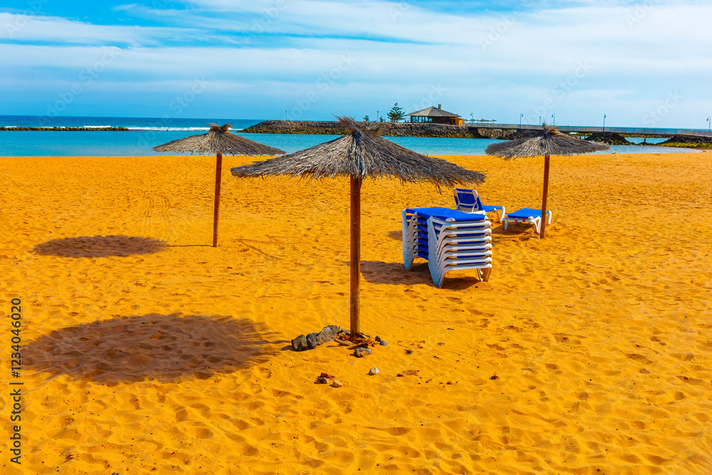 Beach scene with straw umbrellas casting shadows on the sand