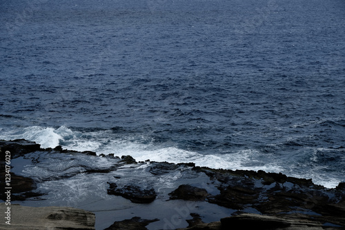 荒々しい波が打ち寄せる岩場と深い青の海