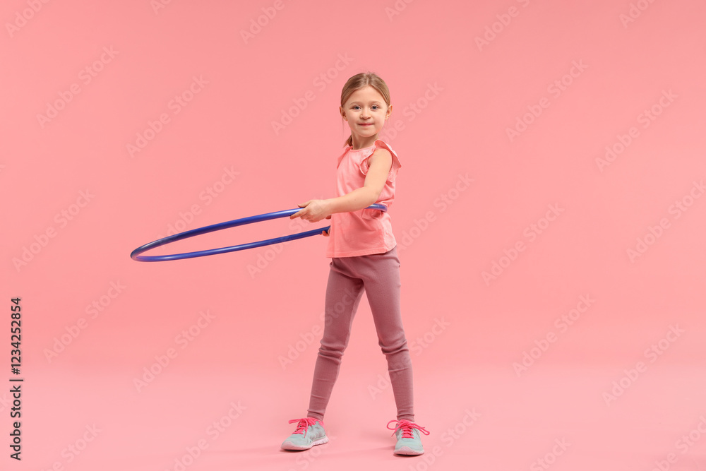 Cute little girl exercising with hula hoop on pink background Cute little girl exercising with hula hoop on pink background