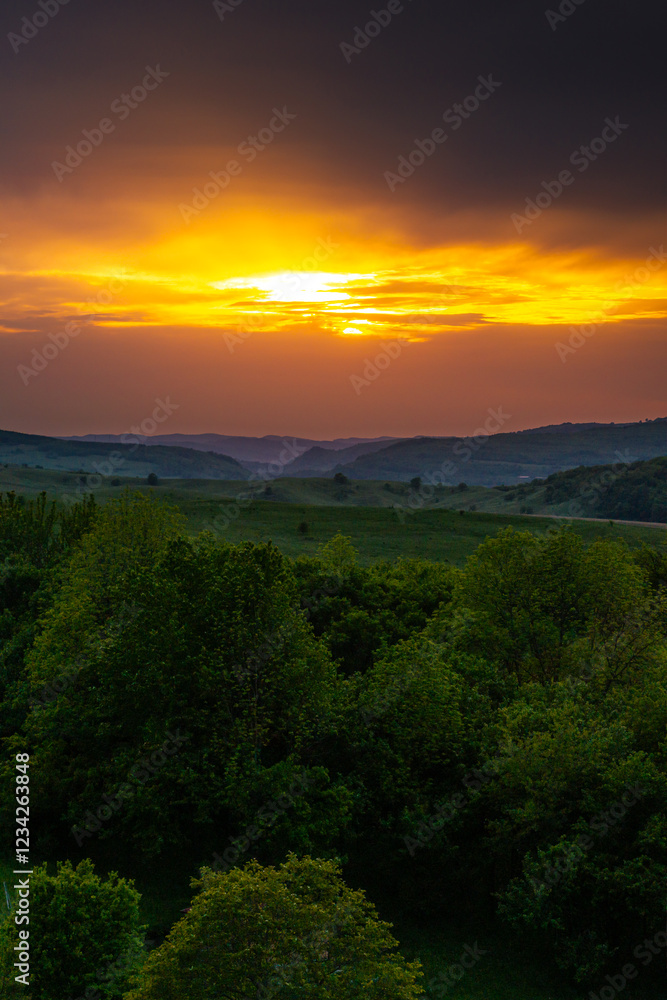Aerial view of the lush green hills of Transylvania during sunset, showcasing the natural beauty and untouched landscapes of this Romanian region. Travel to Romania.