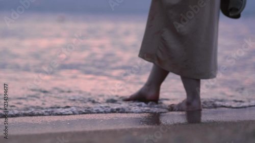  young woman wearing dress walking on the sandy beach sea or ocean at sunset on the water. girl taching woter at night or evening . close up feet on the wave. traveling and relax concept photo