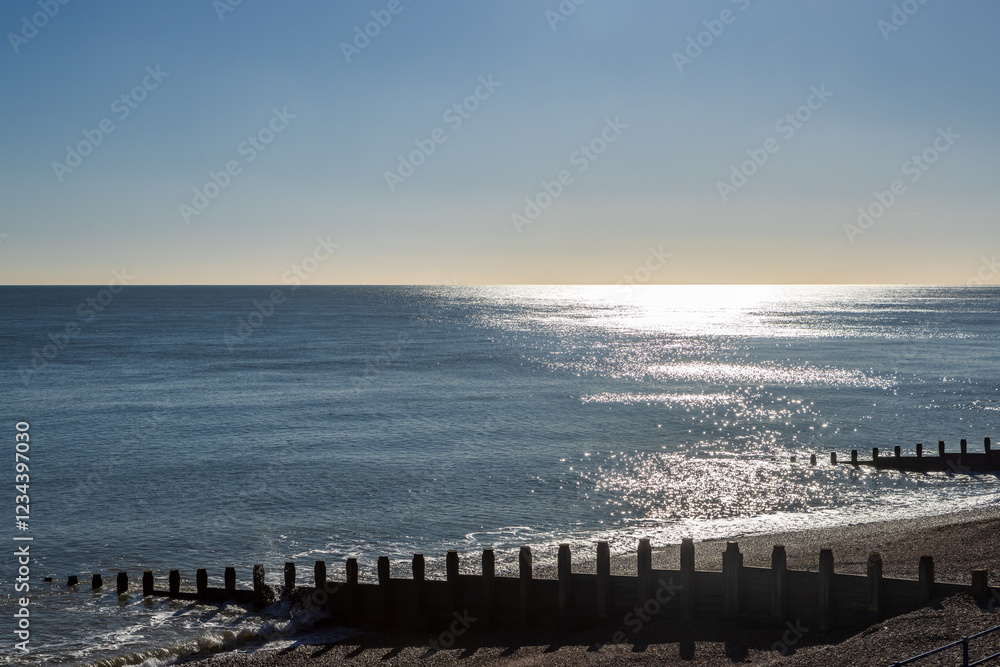Obraz premium A view of the sea over the pebble beach and wooden groynes, on the coast at Eastbourne in Sussex