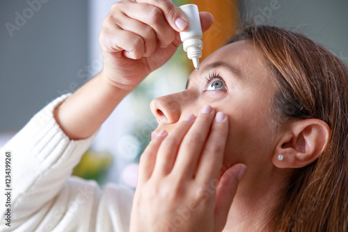Young woman putting eye drops
