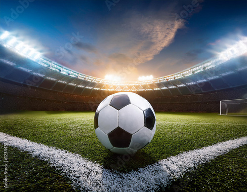 Close up of a soccer ball in the center of the stadium illuminated by the headlights