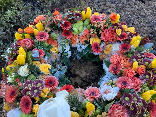 Trauerkranz mit Blumen in Orange und Geld nach Beerdigung auf dem Friedhof im Winter photo