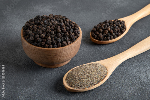 Ground black pepper with grains of black pepper on dark background
