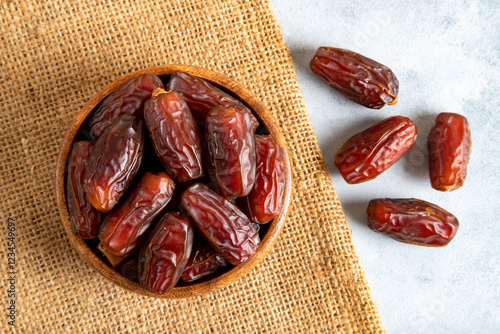 Large dates fruit in a wooden bowl on bright background,top view
