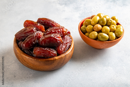 Dates fruit with a bowl of green olive on bright background 