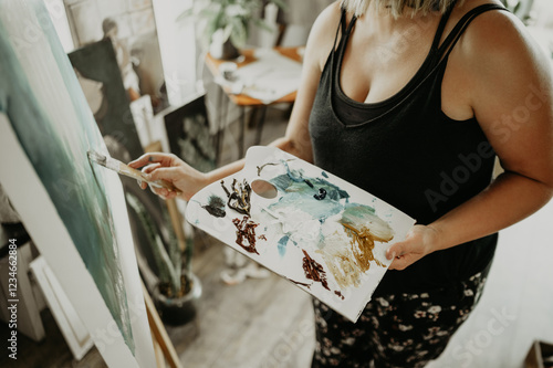 Painting, talent and creative woman in art studio at home with brush, canvas and inspiration with color. Paint, tools and palette, professional artist with vision, freedom and creativity for work. photo