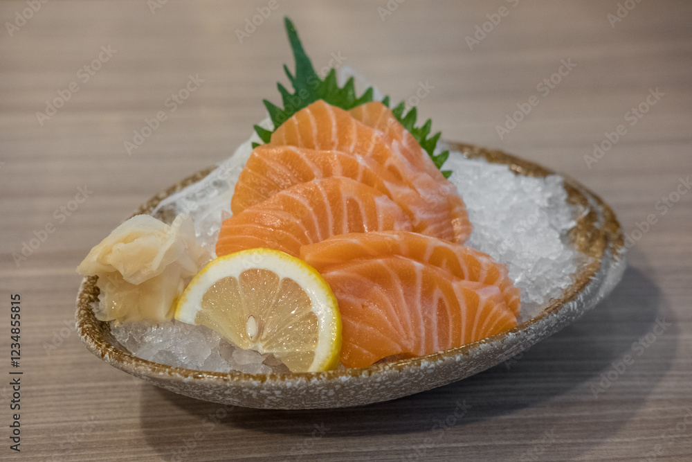 Salmon sashimi with vegetable, lemon and ice in a bowl, served in a restaurant Salmon sashimi with vegetable, lemon and ice in a bowl, served in a restaurant