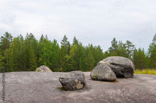 Boulders on a rock against the background of a coniferous forest. White Sea petroglyphs archeological site, Zalavruga, Belomorsk, Karelia, Russia photo