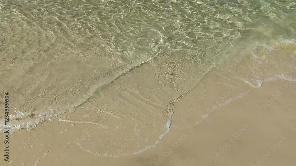 Close up low angle shot of waves breaking on sandy beach on sunny day in summer Close up low angle shot of waves breaking on sandy beach on sunny day in summer