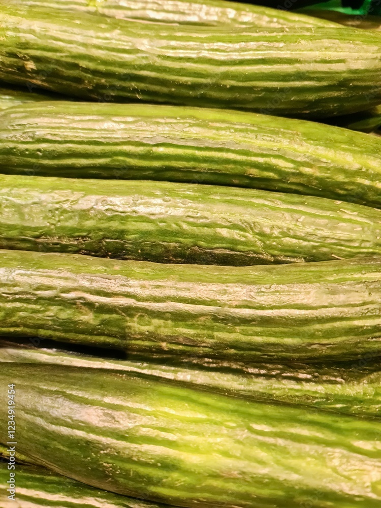 Fresh cucumbers forming a healthy and vibrant green background at the market Fresh cucumbers forming a healthy and vibrant green background at the market