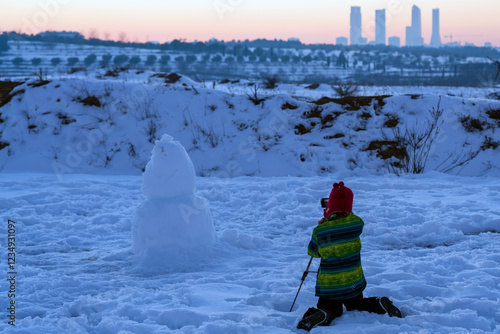 young photographer taking photo of her snowman