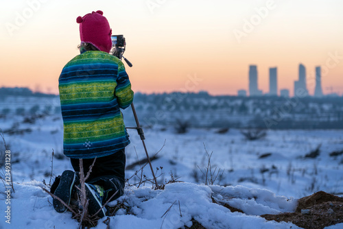 young photographer taking photo of the snowy Madrid dusk