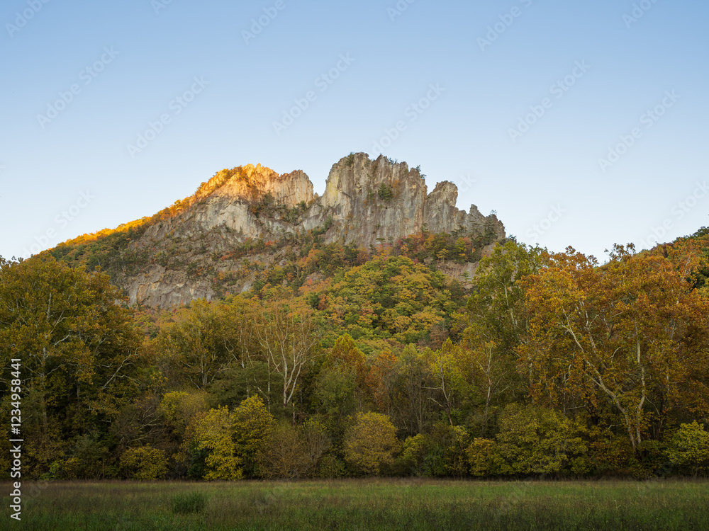 Fototapeta premium Seneca Rocks summit lit in the sunset with trees in fall colors in the foreground