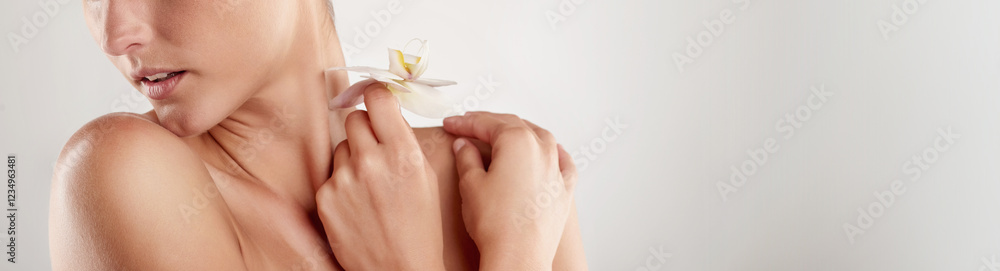 Woman, shoulders or natural beauty with flower for skincare or body hygiene on a white studio background. Closeup, female person or model with orchid on banner for organic dermatology on mockup space Woman, shoulders or natural beauty with flower for skincare or body hygiene on a white studio background. Closeup, female person or model with orchid on banner for organic dermatology on mockup space