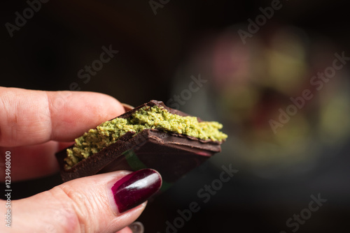 Obraz na płótnie Female Hand Holding Delicious Dark Chocolate with Pistachio Filling. Viral dubai chocolate w salonie