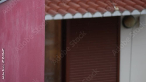 slow motion rain with drops falling on a roof and downspout. photo