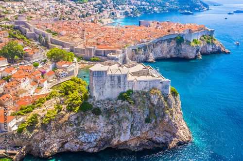 A stunning view from behind Fort Lovrijenac in Dubrovnik, Croatia, capturing the fortress’s massive stone walls, the UNESCO-listed Old Town with its historic architecture and the scenic marina