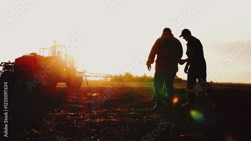 Silhouette of three farmers or tractor workers hand shake for successful deal and agreement in agricultural business, meeting on field at sunset. Agronomists discuss rural machinery, teamwork