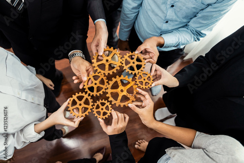 Group of multiracial business people joining gear wheels together as effective unity and productive teamwork concept. Efficient system business team process for solution solving. Meticulous