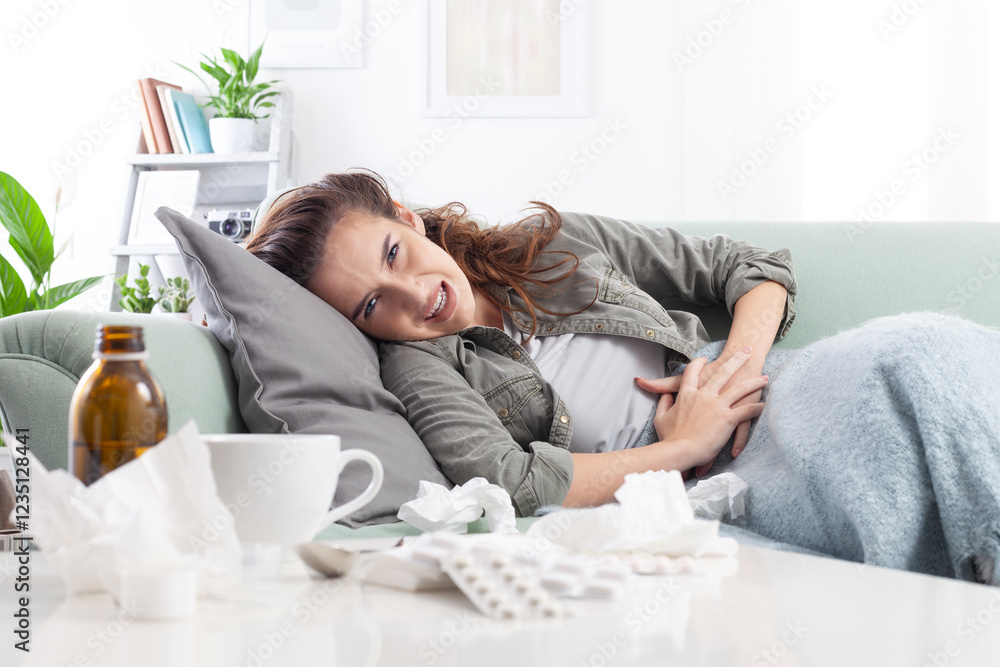 Εκτύπωση καμβά Young woman lying on the couch, holding her stomach in pain, suffering from abdo