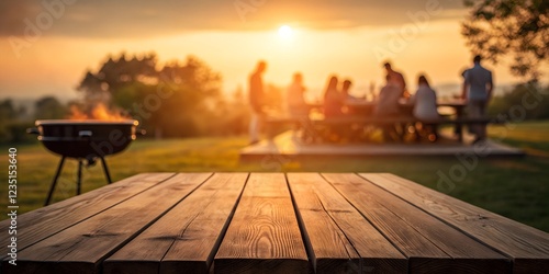 A wooden table in sharp focus with a blurred sunset view of a barbecue gathering, featuring a glowing fire and people enjoying the golden hour outdoors.

