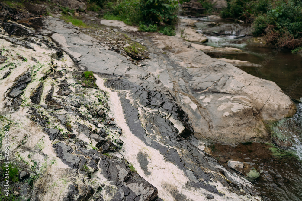 The rocky riverbank. Relief and structure of the stone coast. The water in the river is green The rocky riverbank. Relief and structure of the stone coast. The water in the river is green