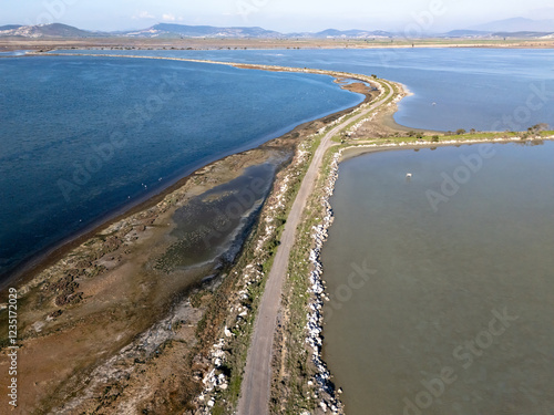 Narrow road dividing calm sea water and salt evaporation ponds in Izmir photo