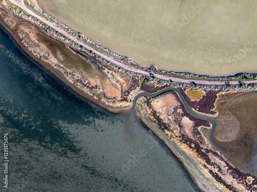 Aerial view of road separating sea water from salt evaporation pond photo