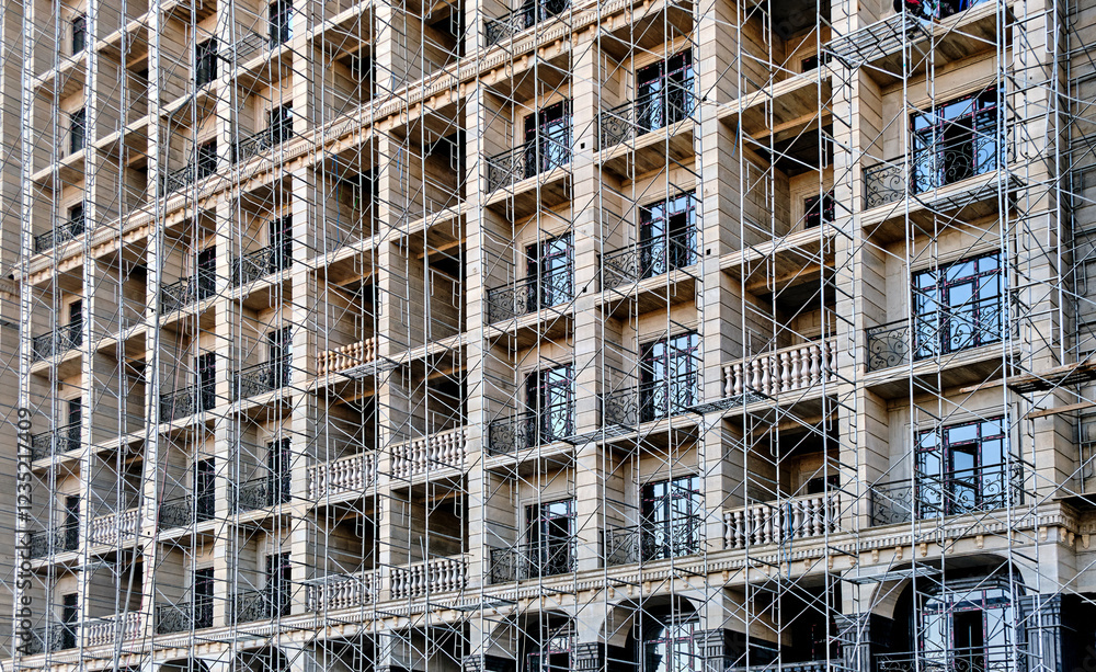 Facade of a multi-story building under construction with scaffolding and balconies. Facade of a multi-story building under construction with scaffolding and balconies.
