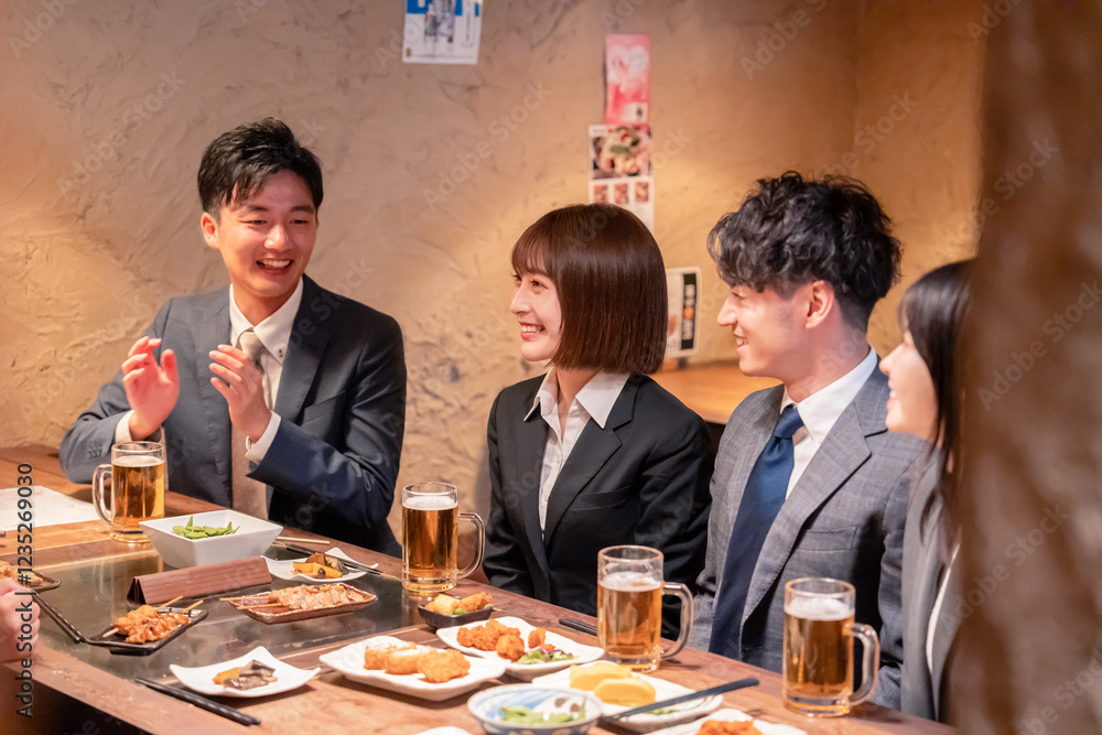 居酒屋で新入社員の歓迎会をするビジネスパーソン