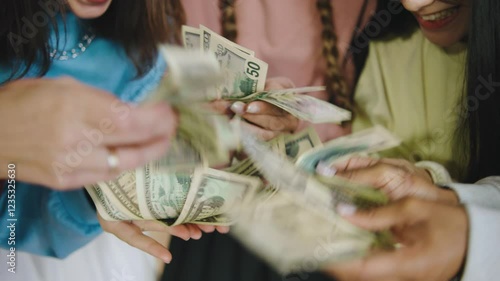 Group of five multiracial female students counting money together in a modern library setting during the afternoon