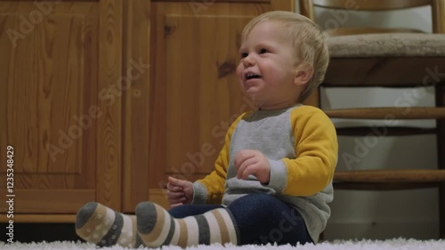 Wallpaper Mural Small toddler with closed eyes joyfully sits on cozy rug, exhibiting playful expressions amid warm and inviting living room, beautifully capturing moment filled with pure joy and innocence Torontodigital.ca