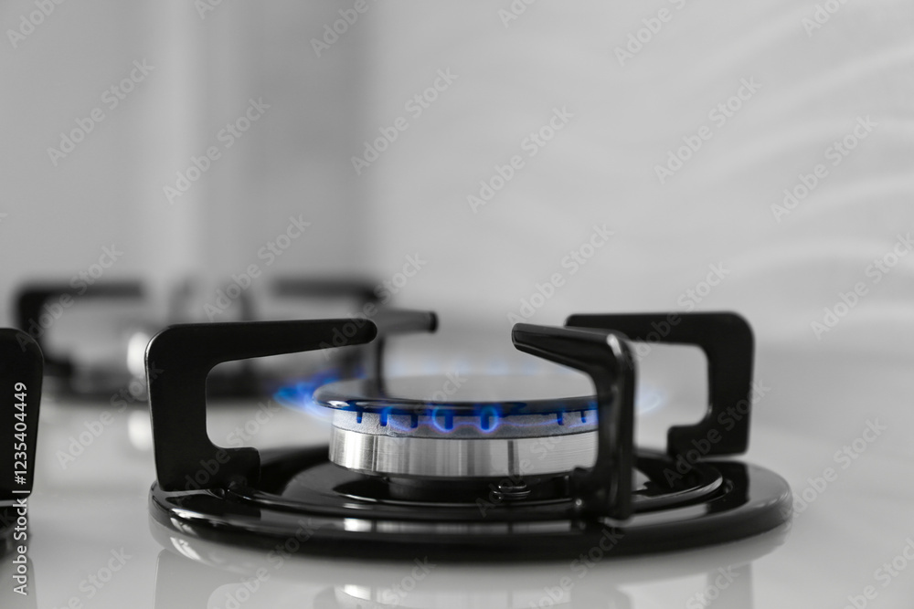 Gas burner of modern stove with burning blue flame, closeup Gas burner of modern stove with burning blue flame, closeup