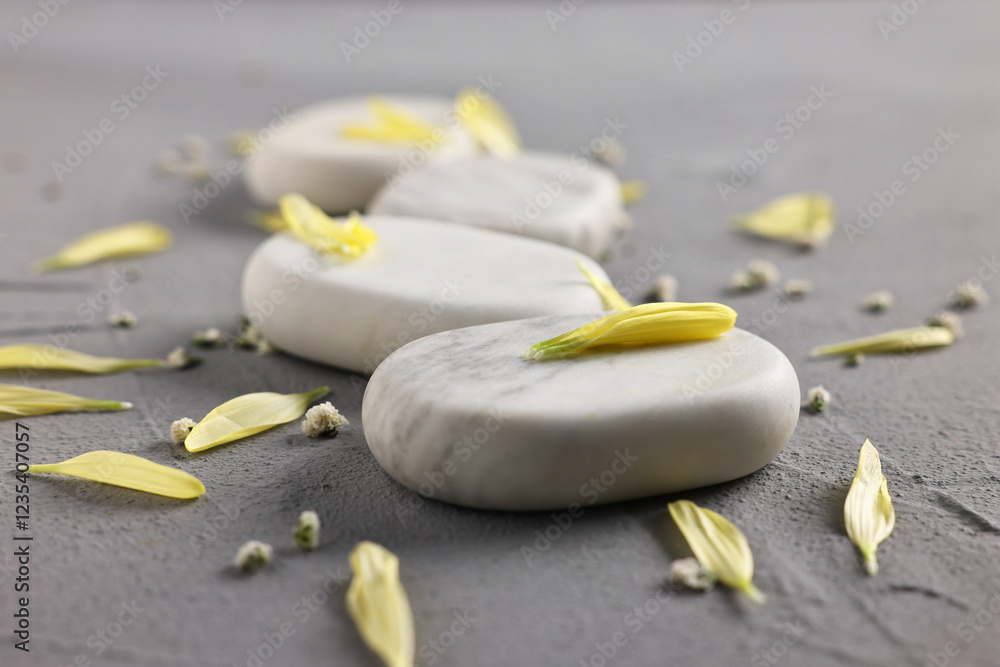 Spa stones, flowers and petals on grey table, closeup Spa stones, flowers and petals on grey table, closeup