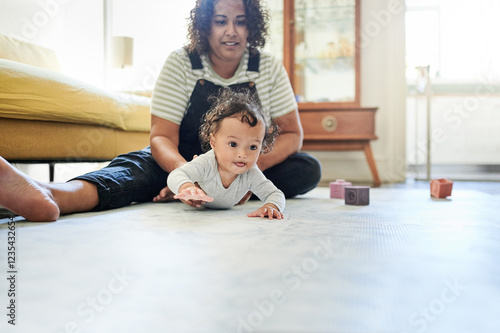 Mother, baby and playing in home living room with toys for development, growth and bonding. Woman and child together for family time, crawling and support while learning for fun on mock up floor photo