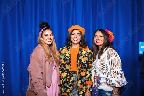 Three south asian women posing together at event backdrop